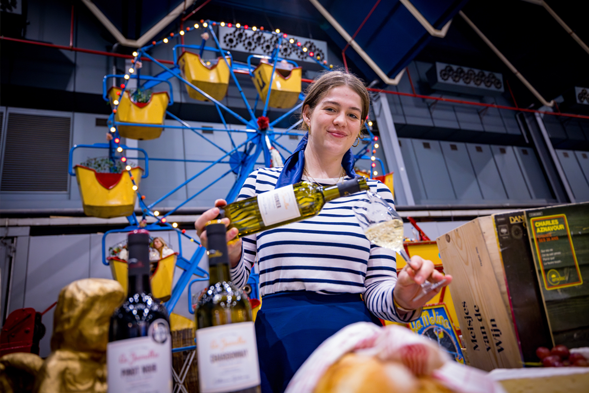 Vrouwelijke sommelier schenkt glas wijn in terwijl ze in de camera kijkt