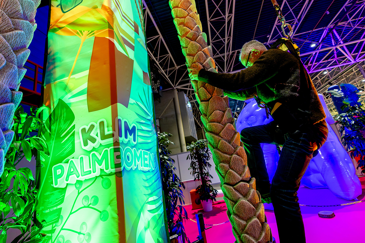 Man die klimt in palmboom op Vakantiebeurs