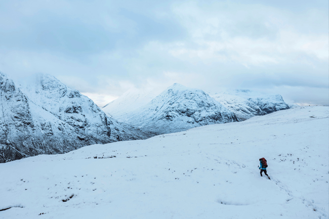Eenzame wandelaar loopt door besneeuwde bergen